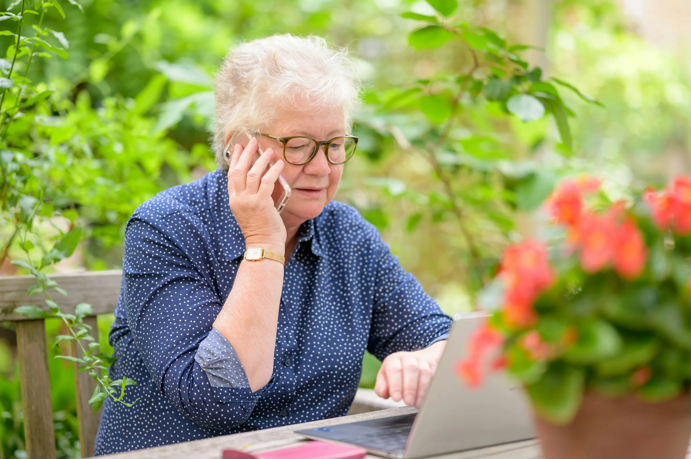 A retiree reviewing her investments on a laptop in a sunny garden
