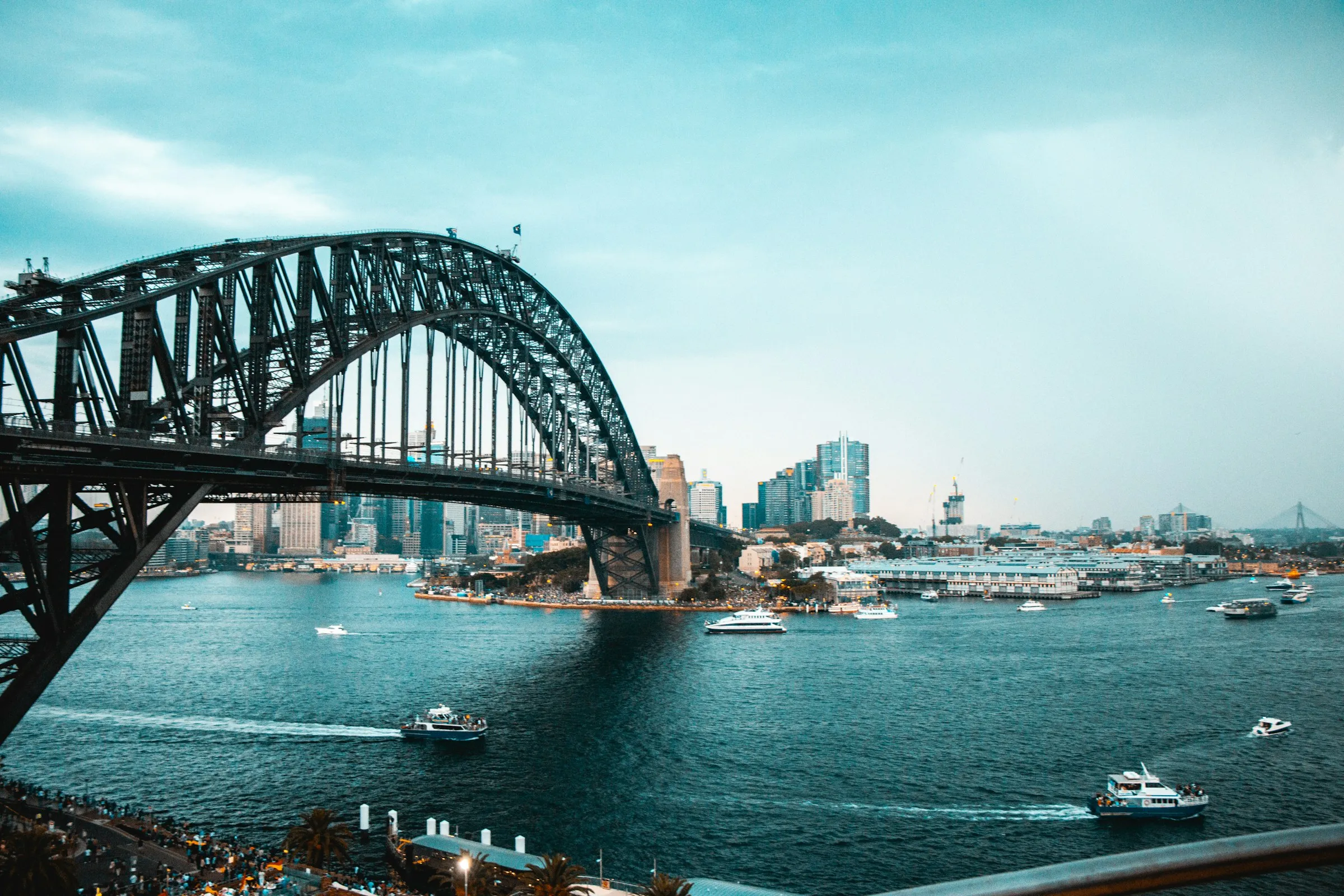 Boats on Sydney Harbour beneath the Harbour Bridge on a sunny day
