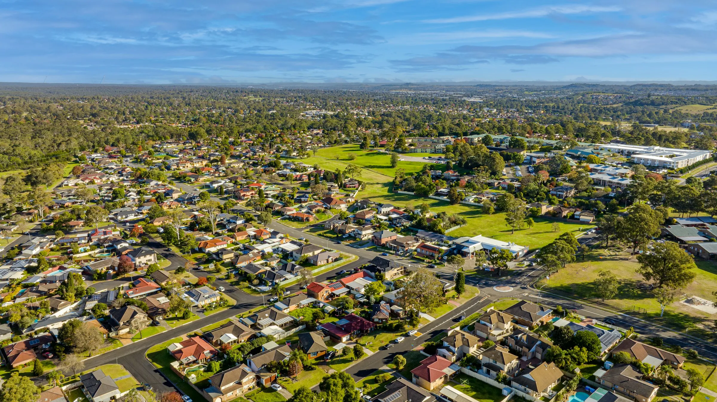 An aerial view of Sydney's suburbs stretching to the horizon, showing the scale of Australia's residential property market